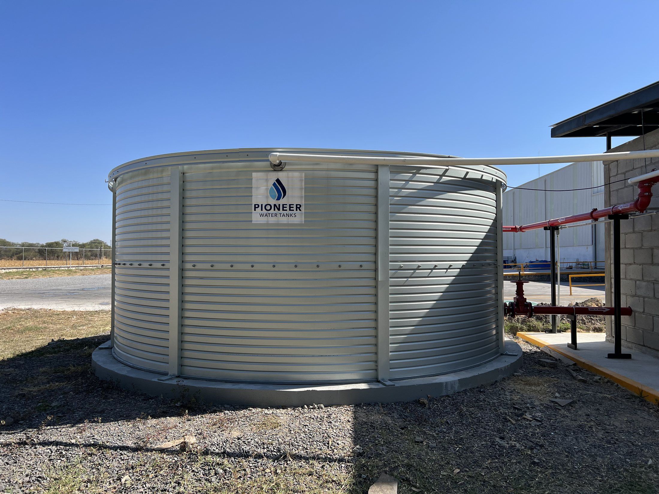 Tanque de acero atornillado para agua contra incendio, terminado en sitio junto a la nave.